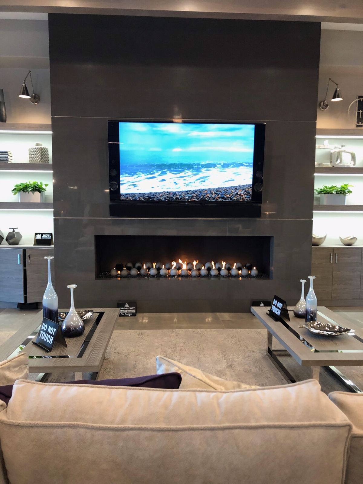 Living room with a tiled fireplace wall, linear fireplace with flames and a mounted TV
