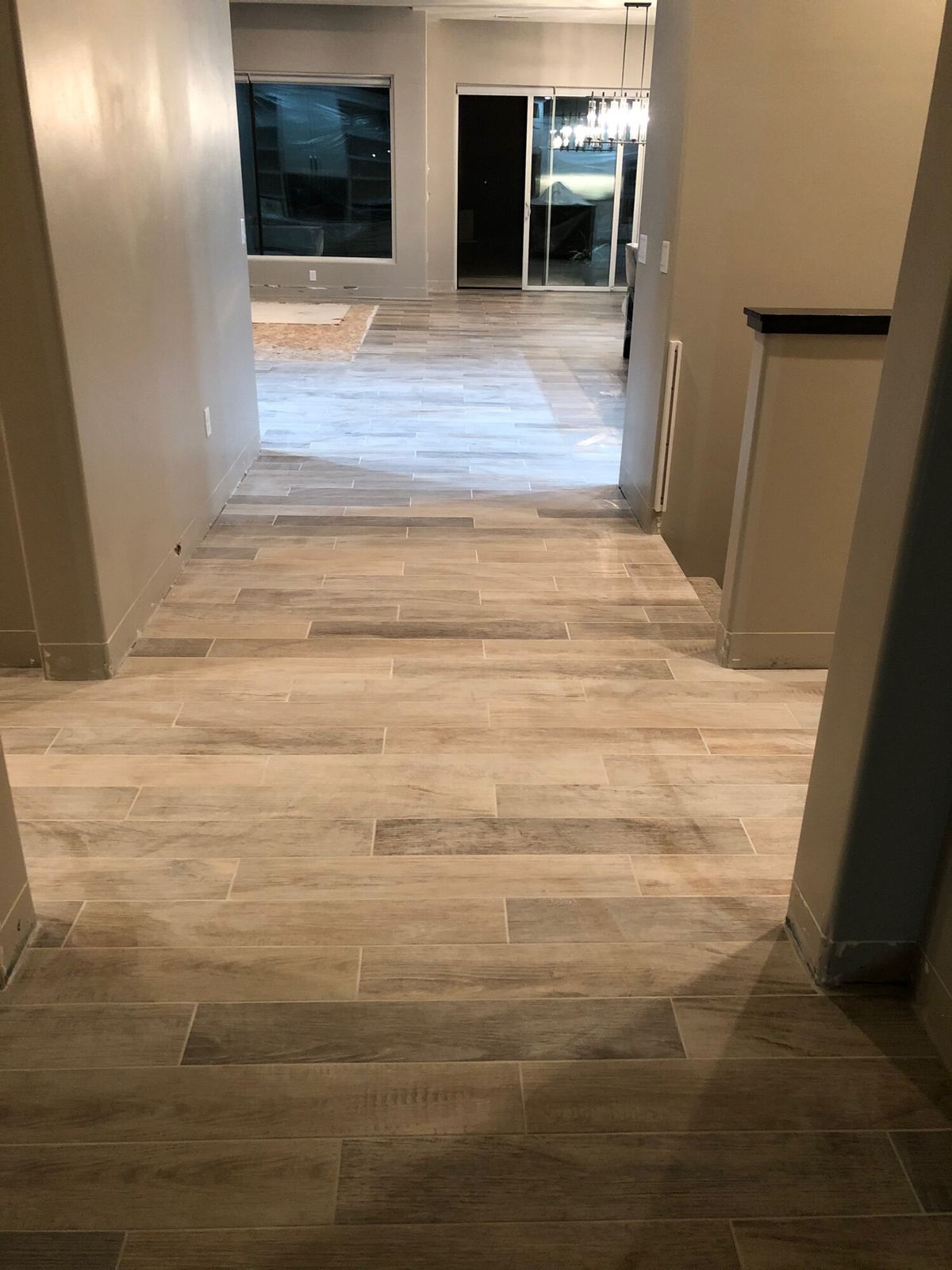 Wood-look plank tile running through a hallway into an open living area