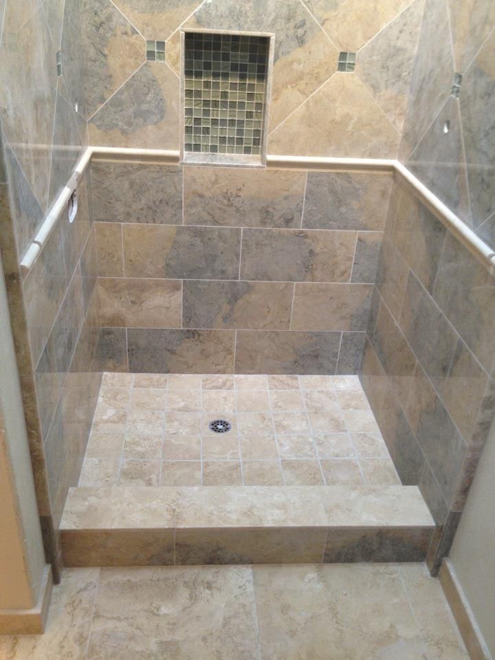 Walk-in shower in stone-look tile set on the diagonal above a rail, with a glass-mosaic niche and a tiled curb