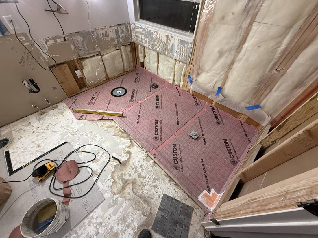 Pink waterproofing membrane laid over the sloped bed with the drain flange in place